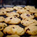 Biscotti della nonna appena sfornati su un piatto, con gocce di cioccolato e zucchero a velo sopra.