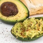Salsa di avocado cremosa in una ciotola, decorata con lime e pepe nero.