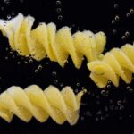 Acqua di cottura della pasta versata in un vaso con piante verdi.