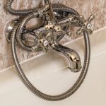 Dettaglio di una bottiglia di aceto accanto a una superficie del bagno con calcare.