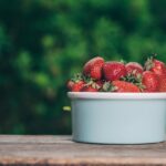 Fragole coltivate in vaso con foglie verdi e frutti rossi, ideali per spazi senza giardino.