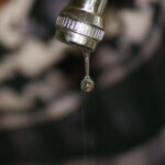 Panno imbevuto di aceto avvolto attorno a un rubinetto per la pulizia e rimozione del calcare.