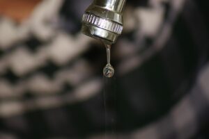 Panno imbevuto di aceto avvolto attorno a un rubinetto per la pulizia e rimozione del calcare.