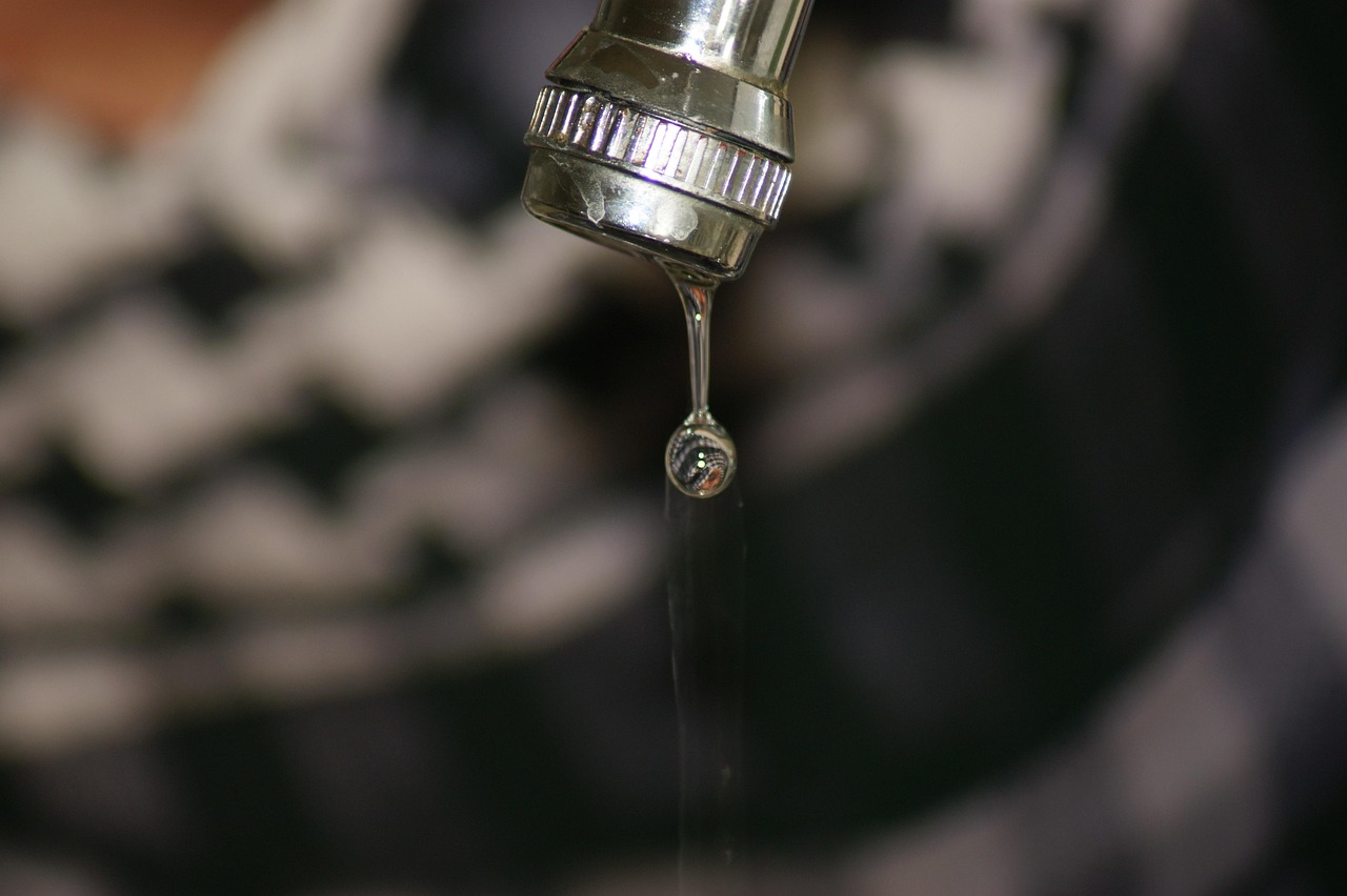 Panno imbevuto di aceto avvolto attorno a un rubinetto per la pulizia e rimozione del calcare.