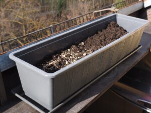 Immagine di un balcone con piante aromatiche e verdure pronte per essere seminate per la raccolta di maggio.