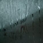 Specchio del bagno appannato con un asciugamano appeso, riflettendo la luce naturale.